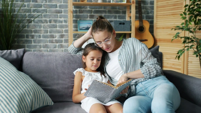 Mother and daughter reading a book together on the couch